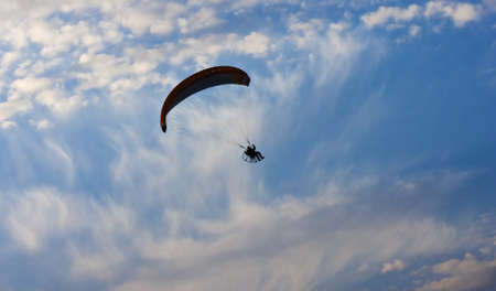 Clear blue sky with white clouds and lone paraglider.の写真素材