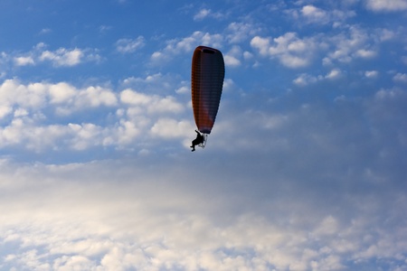 Clear blue sky with white clouds and lone paraglider.