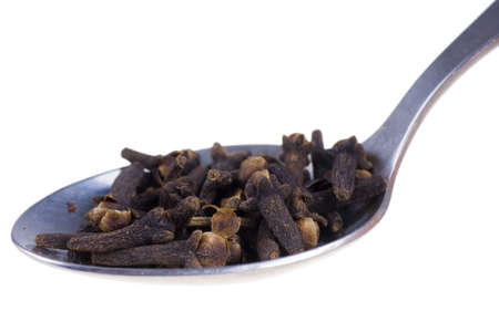 cloves on a spoon isolated on white backgroundの写真素材