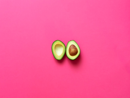 Avocado sliced with seed isolated in fuscia background viewed from above - flatlay look