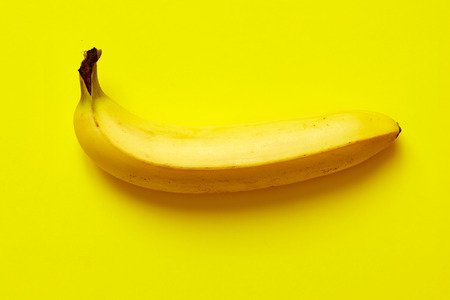 Close up of a ripe banana isolated on yellow background.の写真素材