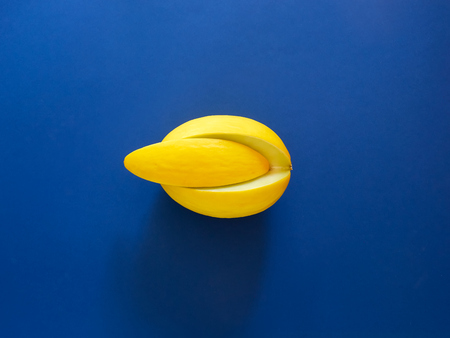 Yellow Melon Fruit isolated in blue background viewed from above - flatlay look - Image Minimalism...