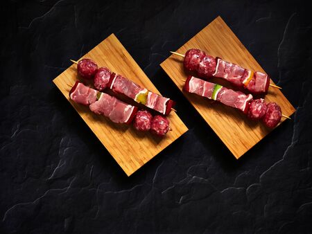 uncooked beef skewers top down view isolated over a wood plank with a dark background in studioの写真素材
