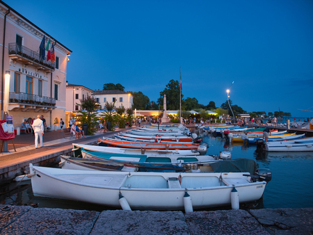 Small fishing boats anchored in the marina of the town of Bardolino on the shores of Lake Garda early at nightのeditorial素材
