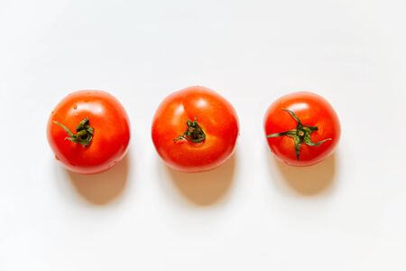 Trio of fresh red tomatos isolated in white background viewed from above - flatlay look