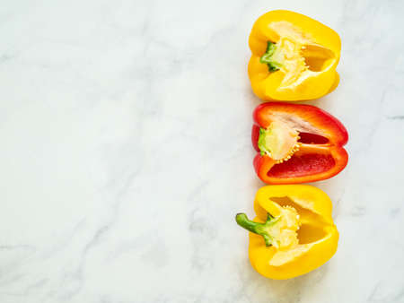Red and yellow bell peppers sliced by the half with seeds isolated in kitchen counter viewed from aboveの写真素材