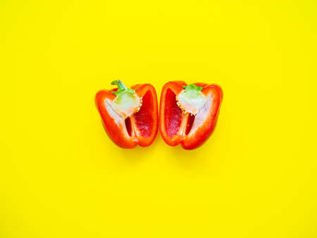 Red bell pepper sliced with seeds isolated in yellow background viewed from above - flatlay look
