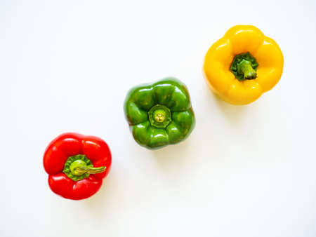 Red, green and yellow bell peppers isolated in white background viewed from above - flatlay lookの写真素材