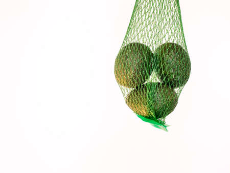 Avocados in a green net  isolated and suspended on air with a white background in studioの写真素材