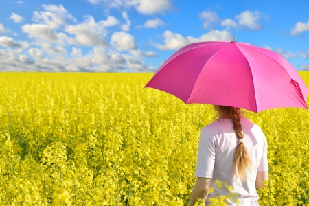 Blonde woman with umbrella in the field of rapeの写真素材