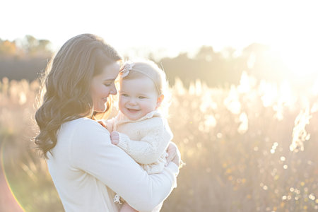 Happy mother with baby in the meadow at sunset. Beautiful family portrait.の素材