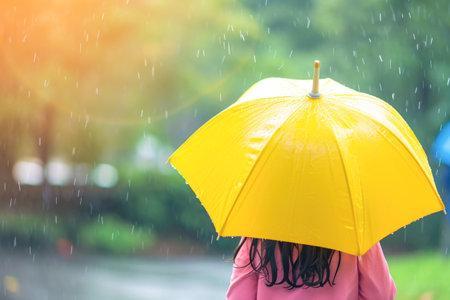 Girl with yellow umbrella in the rain on a rainy day. Close-upの素材