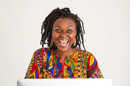 young happy and beautiful black Afro American woman with long braided hair working at computer laptop smiling cheerful in creative business success conceptの素材