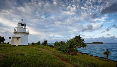 Fingal lighthouse on grassy hill overlooking blue pacific oceanの写真素材