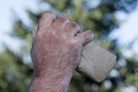 filthy hand of caveman holding handaxeの写真素材