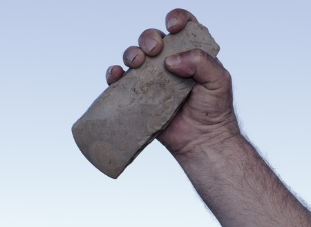 filthy hand of caveman holding handaxeの写真素材