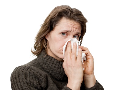 woman having a cold blowing her noseの写真素材