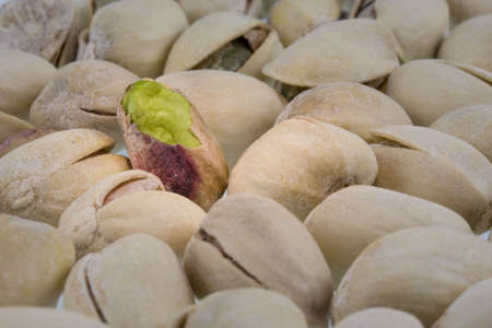 salted pistachios nuts with focus and spot light on a shelled one