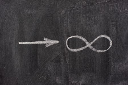 approaching infinity in mathematical symbols handwritten with white chalk on blackboardの写真素材