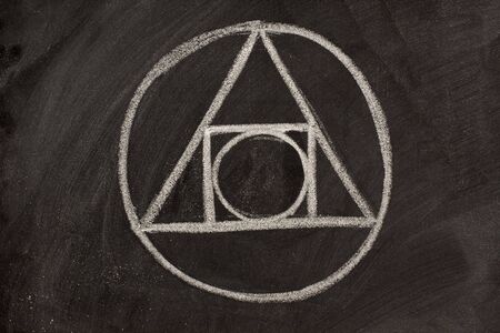 17th century alchemy symbol sketched with white chalk on a blackboard - the blending of geometric shapes, elemental symbols and astrological signsの写真素材