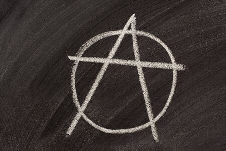 symbol for anarchy sketched with white chalk on a blackboardの写真素材