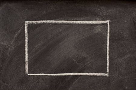 blank rectangle sketched with white chalk on a blackboard with eraser smudges and dustの写真素材