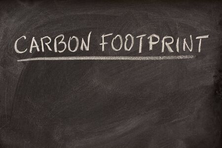 carbon footprint as lecture title or class topic handwritten with white chalk on a school blackboardの写真素材