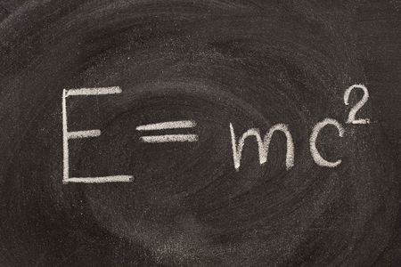 Albert Einstein well known physical formula, E=mc2, describing equivalence of matter mass (m) and energy (E) with including speed of light.  It is hadwritten with white chalk on school blackboard with strong smudge patterns.の写真素材