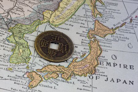 Empire of Japan on a vintage map (1926) and old Japanese coin with square holeの写真素材