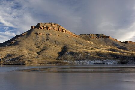 Flatiron Reservoir covered partially by ice surrounded by hills and sandstone cliffs in foothils of Rocky Mountains in Colorado near Lovelandの写真素材