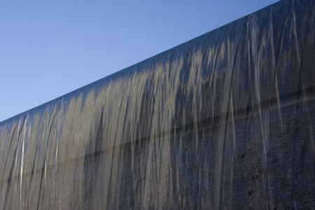 fountain water flowing on granite wall under blue skyの写真素材