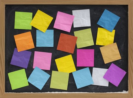 blackboard covered with colorful blank sticky notesの写真素材