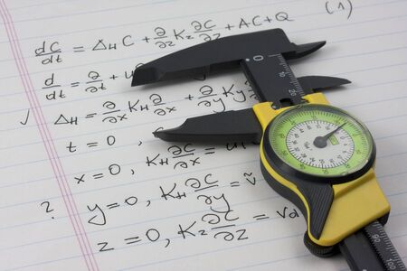 mathematics or physics learning concept - caliper seizing mathematical equations handritten on notebook pageの写真素材