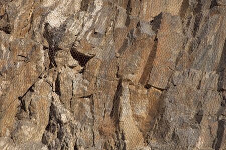 Metal mesh over vertical rock cliff to protect highway below againts falling rocks.の写真素材