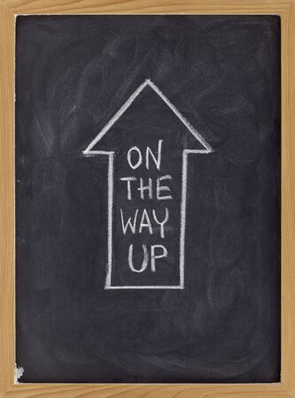 on the way up concept on blackboard - white chalk handriting inside big arrowの写真素材