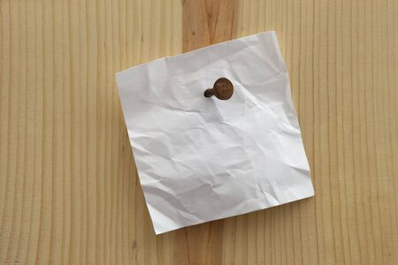 white crumpled blank reminder note nailed to a wooden plank or wallの写真素材