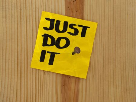 just do it, motivational reminder handwritten on yellow sticky note and nailed to wooden wall or plankの写真素材