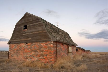 abandoned brick barn and farm buildings in eastern Colorado prairie at duskの写真素材