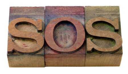 call for help - SOS word in vintage wooden letterpress printing blocks, isolated on whiteの写真素材