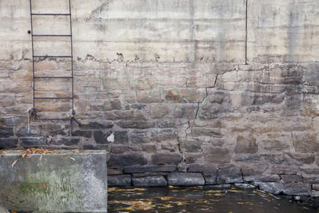 rusty metal ladder on old concrete and stone wall of a river damの写真素材