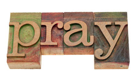 pray word in vintage wooden letterpress printing blocks, stained by color inks, isolated on whiteの写真素材