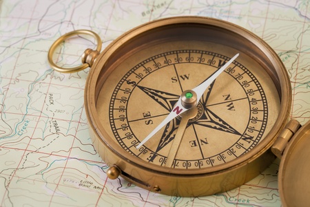 vintage pocket brass compass opened over topographical map