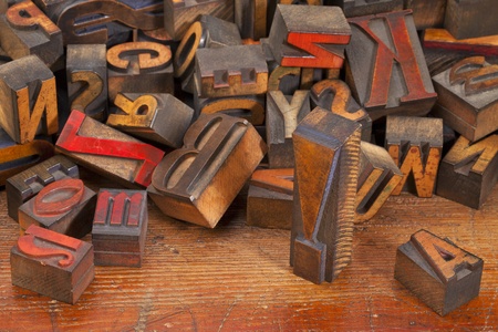 a variety of vintage wooden letterpress printing blocks, stained by color inks,  placed randomly on an old wood surface, focus on exclamation pointの写真素材