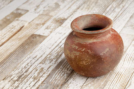 small red and brown clay plant pot (mass produced planter) with rough, grunge finish,  on white wood backgroundの写真素材