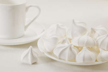 plate of meringue cookies and espresso coffee cup on white tableclothの写真素材