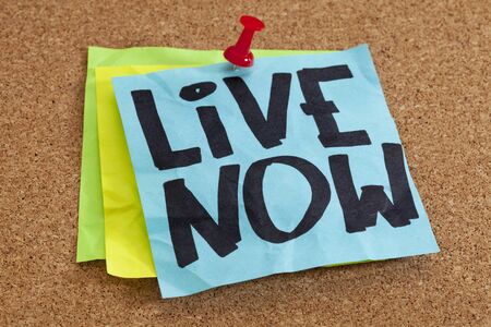 live now reminder on blue sticky note posted on cork boardの写真素材