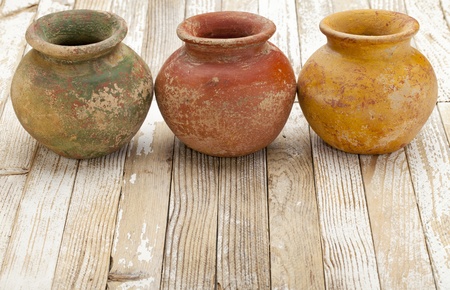 three small  clay plant pots (mass produced planter) with rough, grunge finish,  on white rustic wood backgroundの写真素材