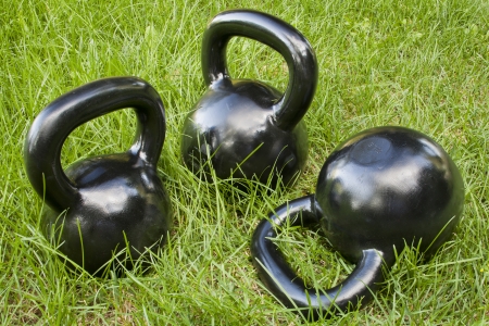 three heavy iron  kettlebells in green grass - outdoor fitness conceptの写真素材