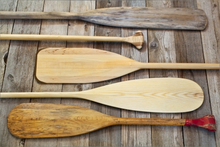 blades and grips of wooden canoe paddles of different shape against grunge wood surfaceの写真素材