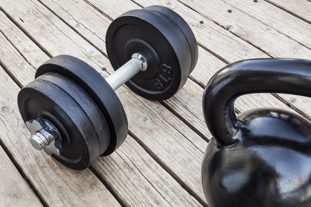 exercise weights - kettlebell and dumbbells on a wooden deck - a home gym conceptの写真素材